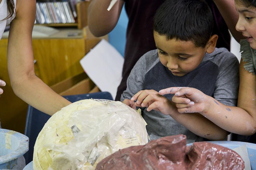 Abiel Montelongo carefully pulls the popped balloon out of the papier-mâché mermaid head.